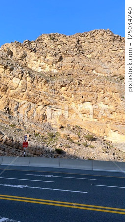 Winding road invites travelers toward rugged mountains, highlighting mountains as scenic tourist destination showcasing natural beauty, adventure spirit, road trips ideal. Winding road invites travelers toward rugged mountains, highlighting mountains as scenic tourist destination showcasing natural beauty, adventure spirit, road trips ideal. 125034240
