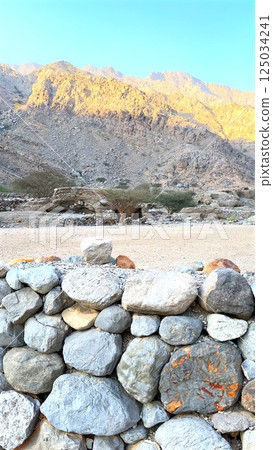 Rugged village with ancient caves carved into rocky hills. Stone walls stand against time, preserving cultural history. Remote landscape reveals heritage of early civilization. Rugged village with ancient caves carved into rocky hills. Stone walls stand against time, preserving cultural history. Remote landscape reveals heritage of early civilization. 125034241