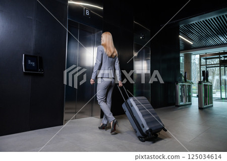 Blonde woman in elegant suit entering the elevator in business center 125034614