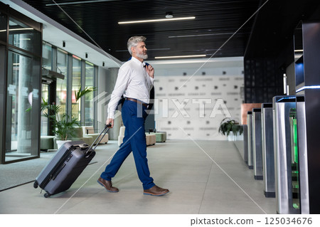 Bearded business tourist with luggage walking to security gates 125034676
