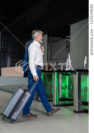 Entrepreneur arriving at airport terminal carrying suitcase 125034688