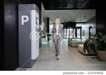 Woman entrepreneur walking through modern workspace in business hub Woman entrepreneur walking through modern workspace in business hub 125034692