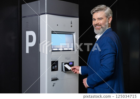 Man paying parking fee using card at automatic machine 125034715