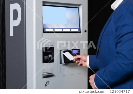 Man in station scanning card to access parking system 125034717
