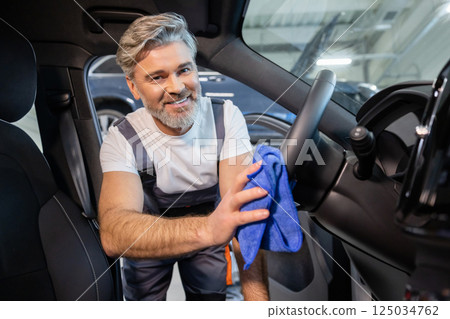 Worker using rag to wipe down dirty transport in garage after repair work Worker using rag to wipe down dirty transport in garage after repair work 125034762