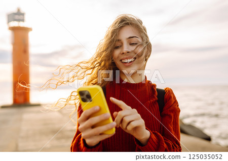Young woman enjoying nature by the waterfront during a cloudy day by a lighthouse. Blogging concept Young woman enjoying nature by the waterfront during a cloudy day by a lighthouse. Blogging concept 125035052