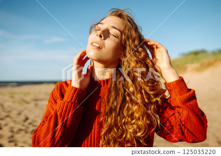 Outdoor portrait of pretty woman on the beach in cold sunny weather. Travel, fashion, blogging 125035220