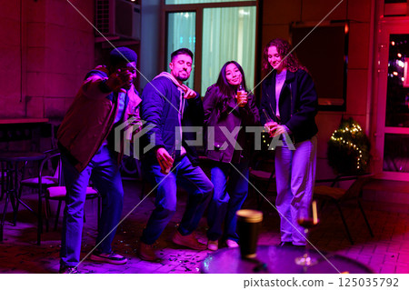 Friends enjoying a lively night out at a vibrant urban lounge with colorful lights and drinks 125035792