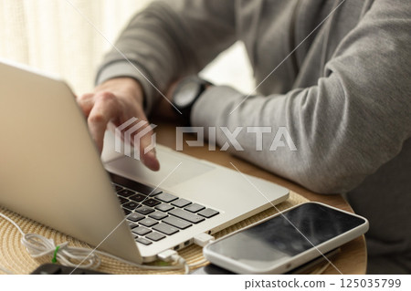 Man working behind a laptop from home wearing sport cozy clothing. Selective focus. 125035799