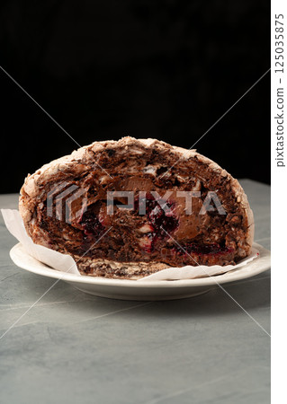 Chocolate dessert served on a plate with layers of rich creamy filling and chocolate chunks during a stylish dining experience Chocolate dessert served on a plate with layers of rich creamy filling and chocolate chunks during a stylish dining experience 125035875