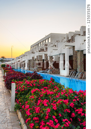 Vibrant flowers and serene water feature at a resort during sunset in a tropical location Vibrant flowers and serene water feature at a resort during sunset in a tropical location 125035876