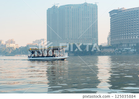 Boat gliding on water near city skyline during morning light in Cairo 125035884