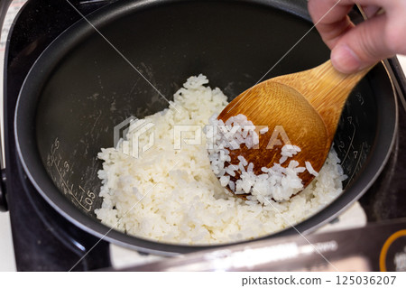 用飯匙把電鍋裡煮好的米飯弄松 125036207