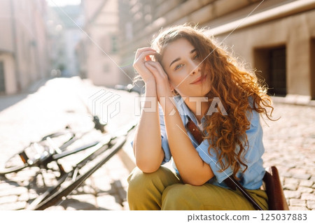 Portrait of smiling woman sitting next to bike on street city. Travel, weekend and lifestyle concept Portrait of smiling woman sitting next to bike on street city. Travel, weekend and lifestyle concept 125037883