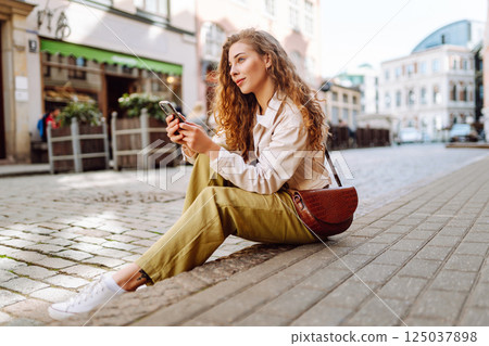 Happy woman using phone walking in city street. Lifestyle, travel, tourism, technology, blogging 125037898