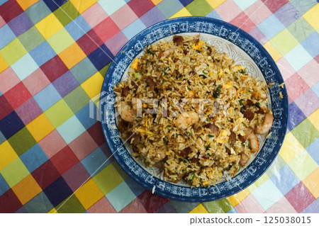 Close up of homemade Chinese Canton style shrimp char siu pork egg fried rice on a plate with colourful table cloth 125038015
