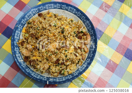 Close up of homemade Chinese Canton style shrimp char siu pork egg fried rice on a plate with colourful table cloth Close up of homemade Chinese Canton style shrimp char siu pork egg fried rice on a plate with colourful table cloth 125038016