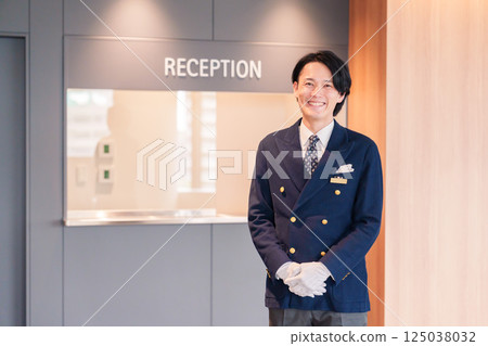 A male hotel attendant serving customers with a smile 125038032
