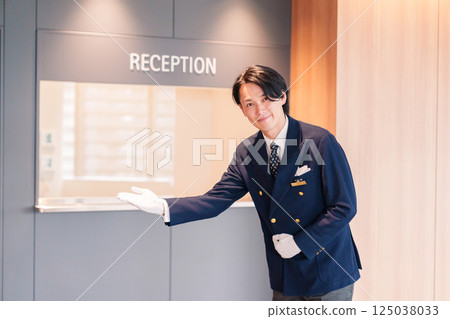 A male hotel attendant serving customers with a smile A male hotel attendant serving customers with a smile 125038033