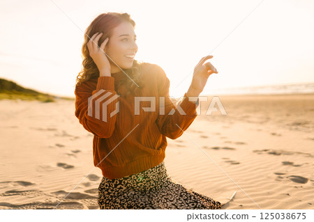 Portrait of a beautiful woman on the beach at sunset. Girl walks along the beach and enjoys weather Portrait of a beautiful woman on the beach at sunset. Girl walks along the beach and enjoys weather 125038675