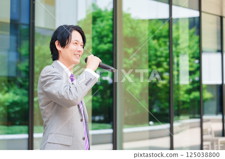 一名西裝革履的男子在街頭用麥克風發表演講 125038800