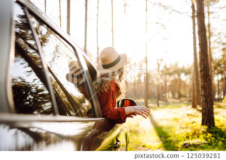 Young woman leaning out of the car window enjoying nature. Road trips summer holidays. 125039281