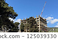 concrete structure under construction with tall red construction crane 125039330