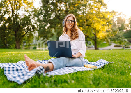 Young woman headphones sits listen to music use mobile cell phone. Concept for business, freelance. 125039348