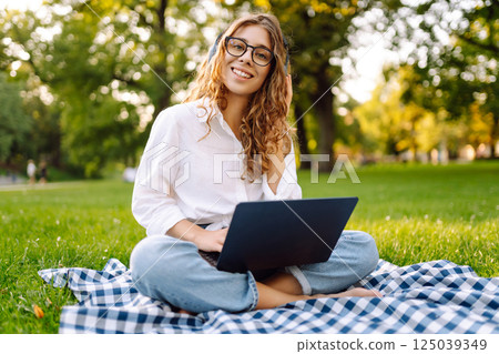 Young woman headphones sits listen to music use mobile cell phone. Concept for business, freelance. 125039349
