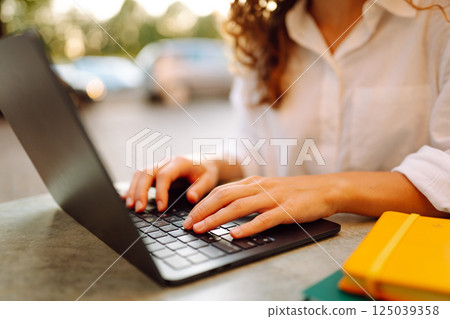 Close-up of woman hands working on laptop outdoors. Freelancing concept, business. 125039358