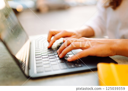 Close-up of woman hands working on laptop outdoors. Freelancing concept, business. 125039359