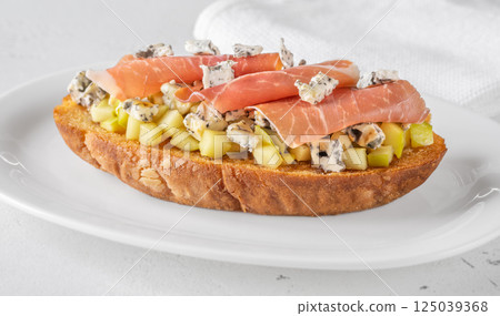 Toasted sandwich with blue cheese, prosciutto, sauteed apple, honey, white plate 125039368