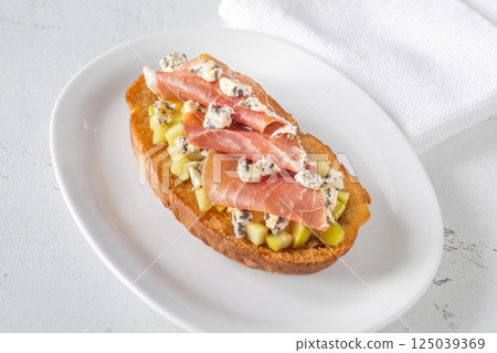 Toasted sandwich with blue cheese, prosciutto, sauteed apple, honey, white plate 125039369