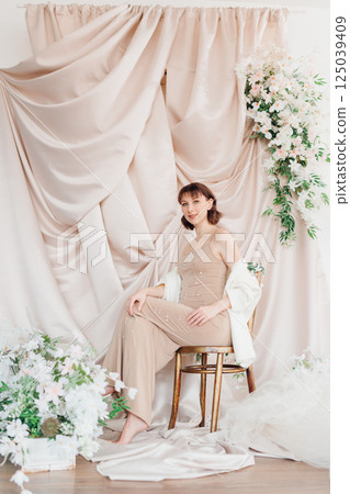 Expecting woman poses beautifully in a calm, floral indoor setting 125039409
