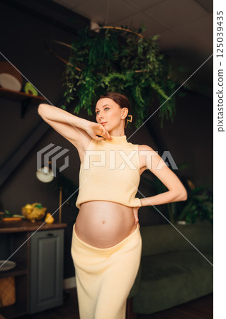 Pregnant young woman poses creatively in a cozy indoor setting 125039435