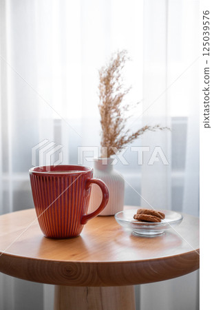 Cozy coffee setup with cookies and dried flowers on wooden table in living room. Cozy coffee setup with cookies and dried flowers on wooden table in living room. 125039576
