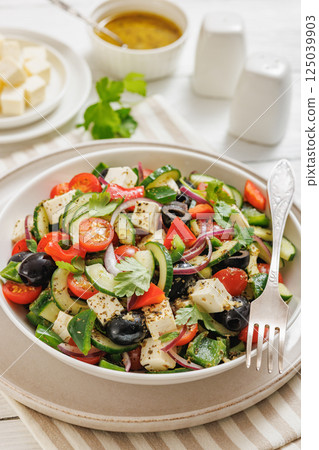 greek salad of veggies, olives, cheese in bowl 125039903