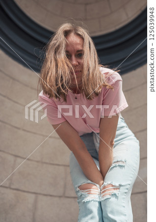 Joyful Young Woman Leaning Against Stone Wall 125039948