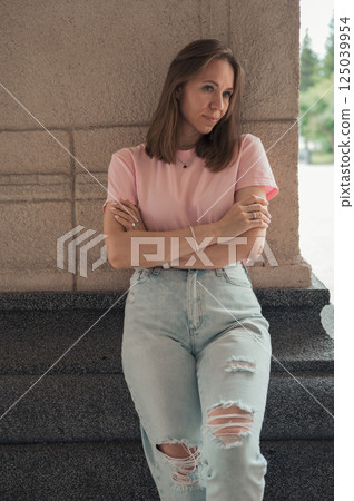 Casual Young Woman Leaning Against Stone Wall 125039954