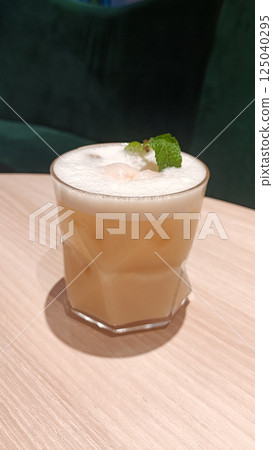 Creamy Iced Milk Tea with Mint Garnish in a Stylish Modern Setting on Wooden Table 125040295
