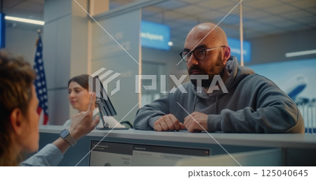 Man Giving Documents and Airplane Ticket, Verifying Biometric Data by Scanning Fingerprint Man Giving Documents and Airplane Ticket, Verifying Biometric Data by Scanning Fingerprint 125040645