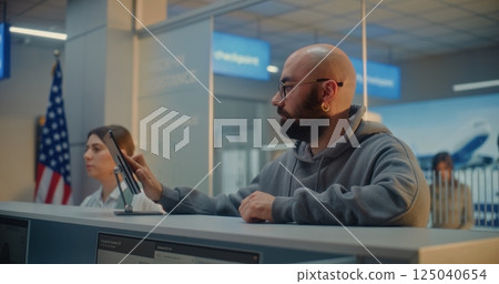 Man Giving Documents and Airplane Ticket, Verifying Biometric Data by Scanning Fingerprint Man Giving Documents and Airplane Ticket, Verifying Biometric Data by Scanning Fingerprint 125040654