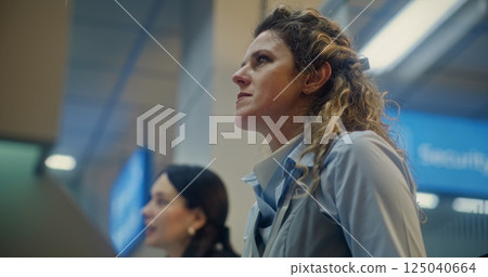 Female Airline Worker Talking and Checking Documents of Passenger at Airport Check-in Counter 125040664