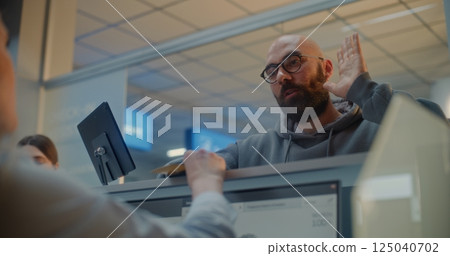 Female Airline Worker Checking Personal ID Data on Computer, Giving Passport and Airplane Ticket to Man 125040702
