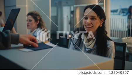 Male Passenger Giving Passport and Flight Ticket to Female Airline Agent at Airport Check-in Counter 125040807