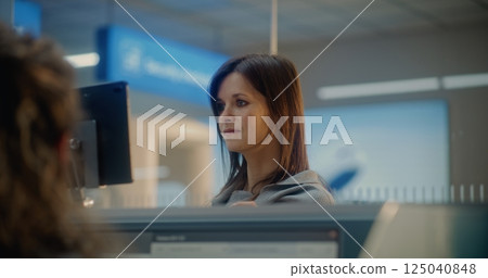 Check-in Counter: Woman Verifying by Facial Recognition. Female Airline Agent Giving Documents 125040848