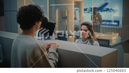Airport Check-in Counter: Female Airline Worker Talking to Young Man During Passport Check 125040883