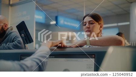 Female Airline Worker Checking Personal Data on Computer, Giving Documents and Boarding Pass to Woman Female Airline Worker Checking Personal Data on Computer, Giving Documents and Boarding Pass to Woman 125040952