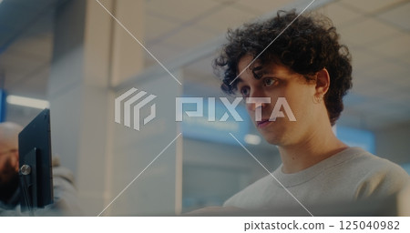 Young Man Verifying by Facial Recognition, Talking to Airline Worker During Passport Check 125040982