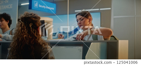 Multiethnic Passengers at Airport Check-in Counter: Female Airline Worker Checking Documents 125041006